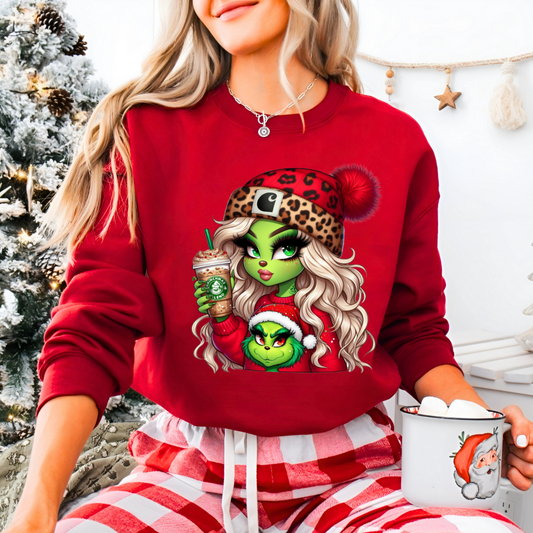Woman wearing a red Christmas shirt with a green-skinned cartoon girl holding a holiday drink and a festive companion in a Santa hat.