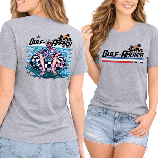 Gray t-shirt with Donald Trump on a raft and 'Gulf of America' design on front and back, worn by a person.