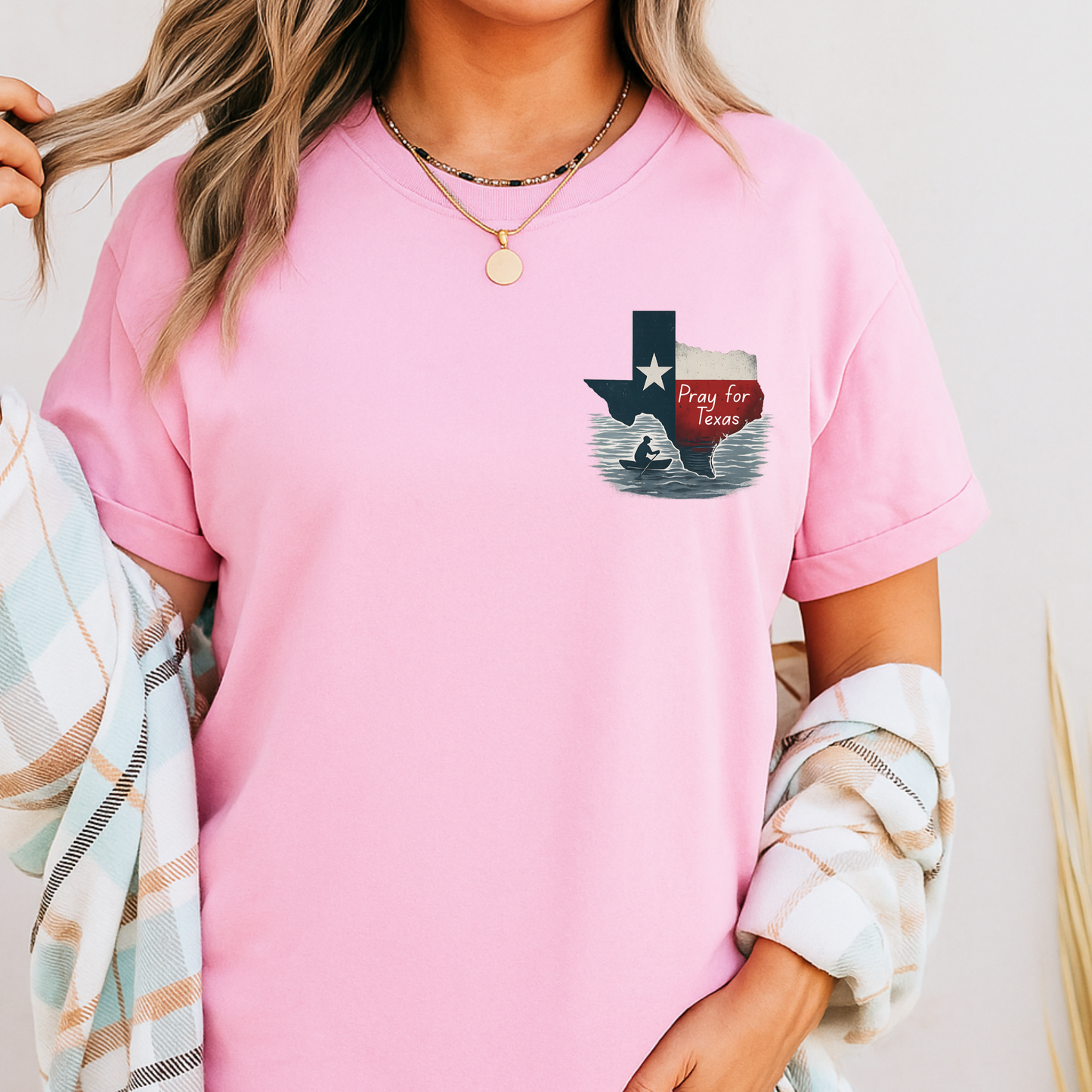 Person wearing a pink t-shirt with a graphic design on a plain background