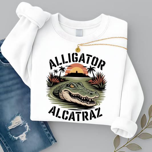 Women’s white Alligator Alcatraz sweatshirt, vintage wildlife graphic with tropical sunset and alligator design, styled flat lay with jeans and gold necklace