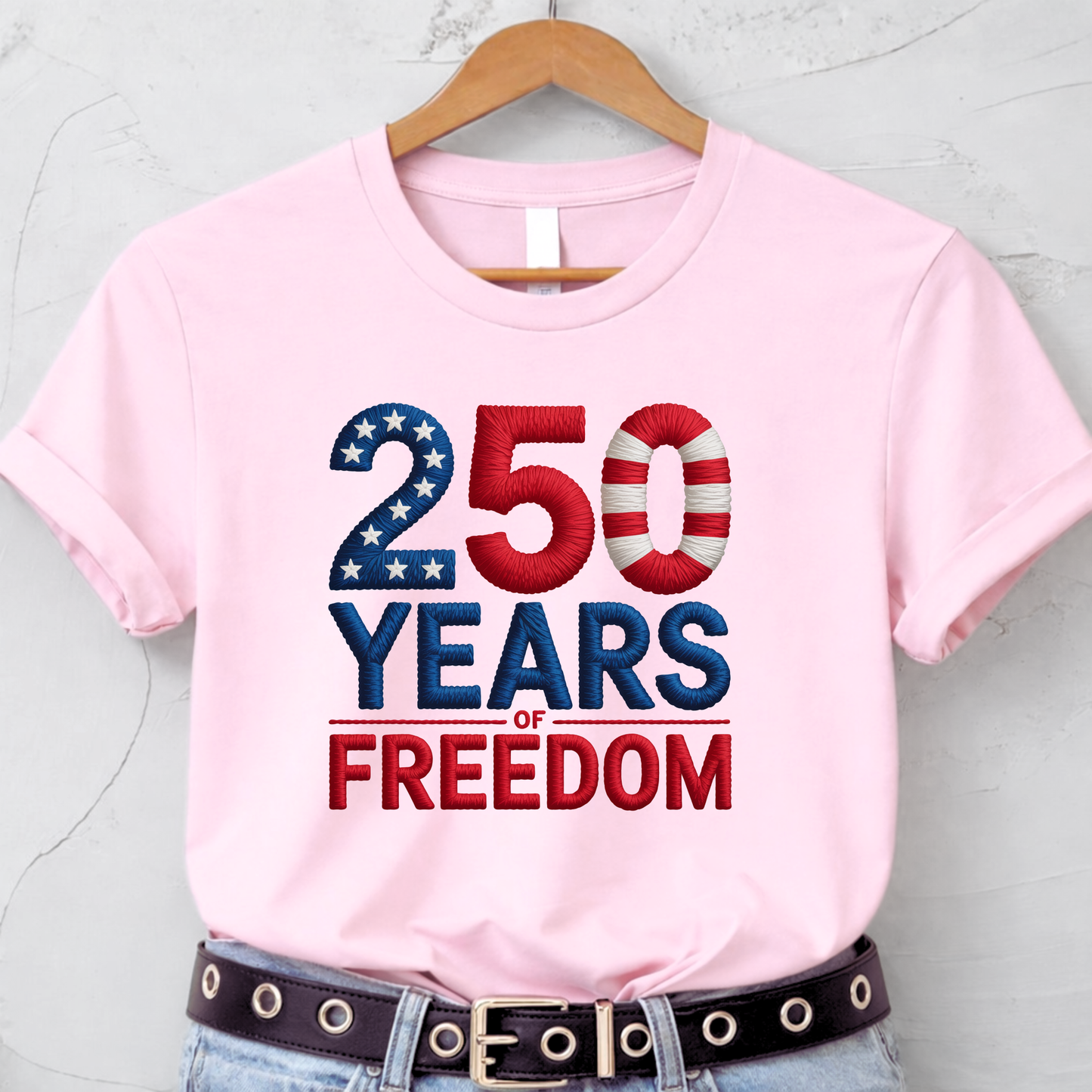 Light pink T-shirt with 250 Years of Freedom patriotic design hanging on hanger