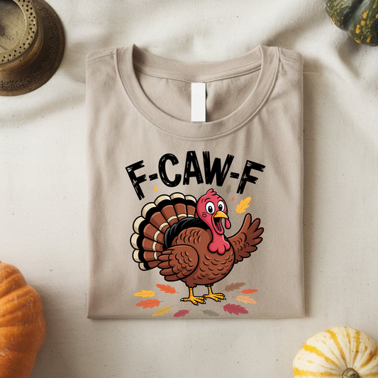 Folded sand color F-CAW-F Thanksgiving shirt with cartoon turkey print