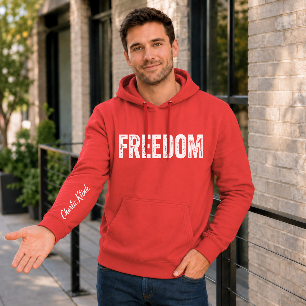 Man wearing a red FREEDOM hoodie with Charlie Kirk signature printed on the inside sleeve.