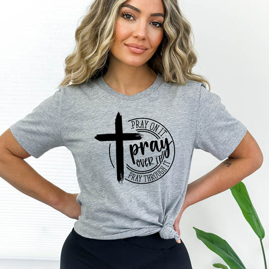 Gray Woman wearing tan T-shirt with black cross graphic and inspirational pray wording.