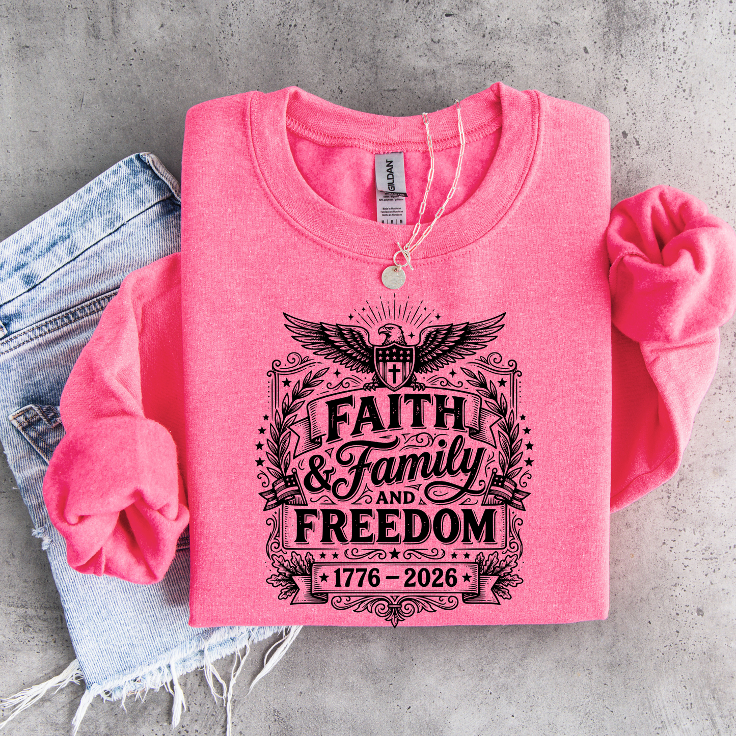 Pink sweatshirt with 'Faith & Family & Freedom' text on a concrete surface