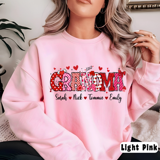 A woman sitting wearing a pink custom sweatshirt with 'Gramma' printed on the front along with hearts and the names 'Sarah, Nick, Tatum, Emily'.