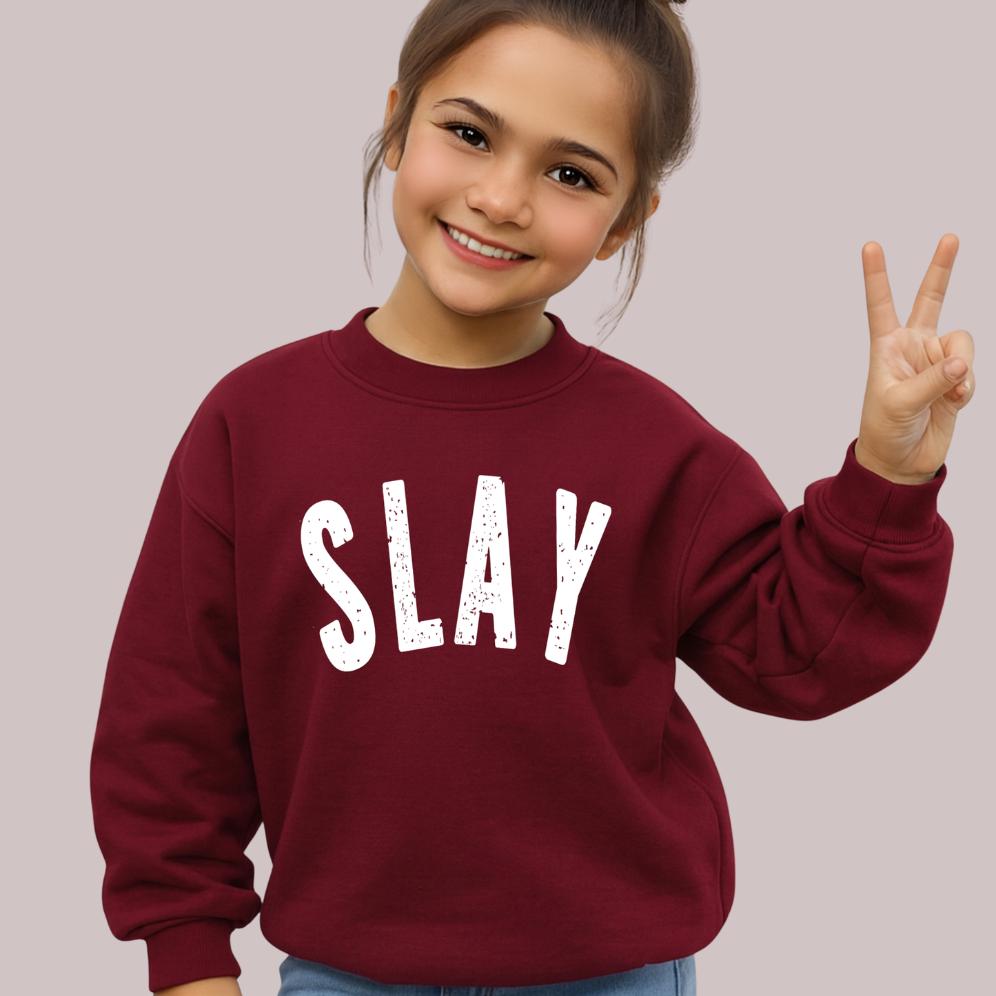 Girl wearing maroon SLAY sweatshirt giving peace sign