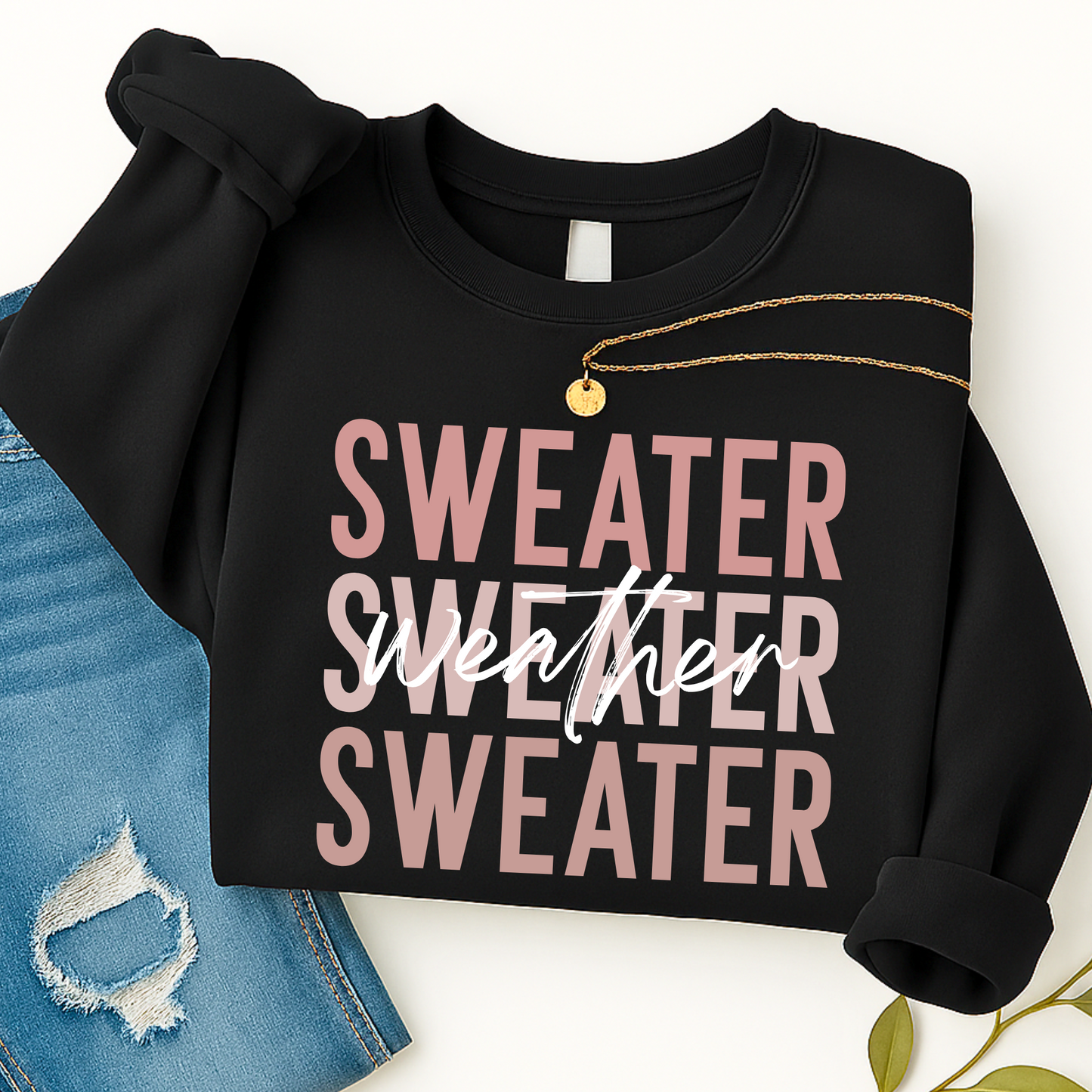 Black Sweater Weather sweatshirt folded with gold necklace and jeans. Cozy unisex fall crewneck perfect for women’s casual outfits and winter layering