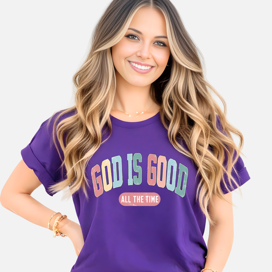 Woman wearing a purple t-shirt with 'God is Good All the Time' text on a plain background