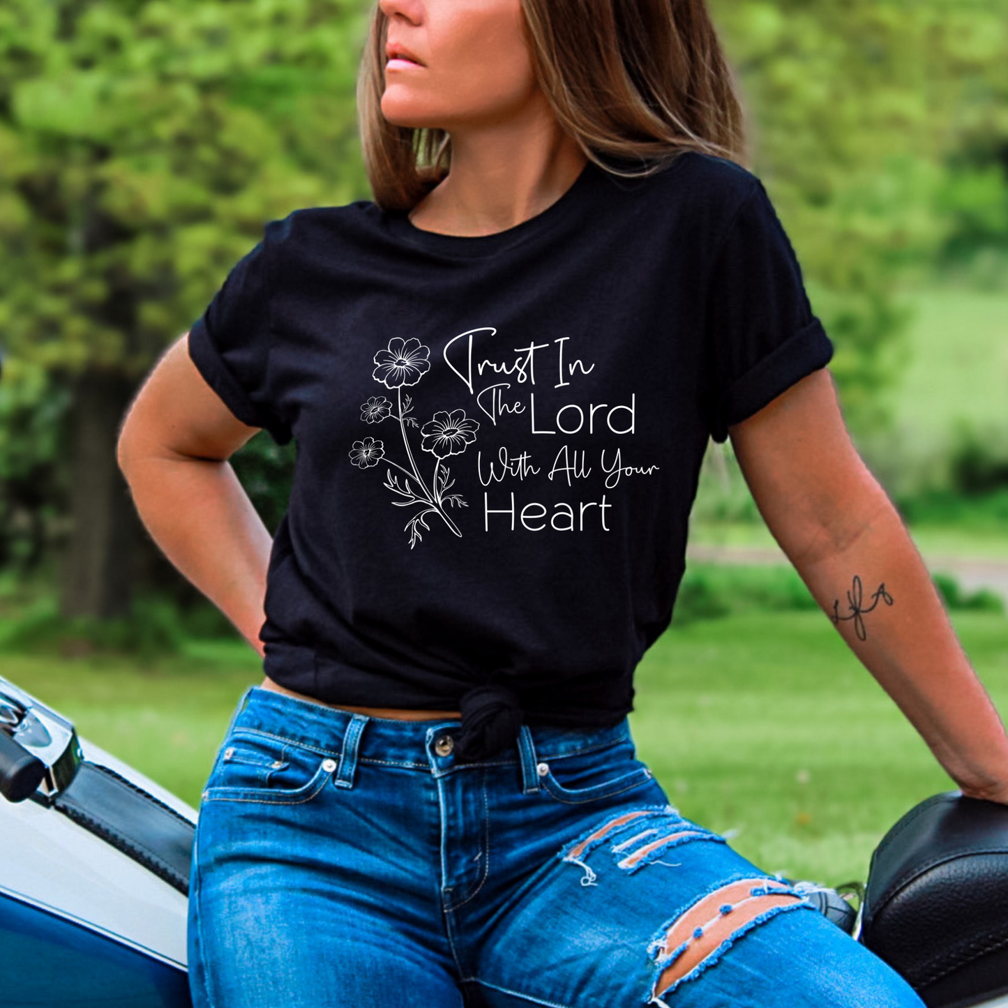 Woman wearing black T-shirt with floral graphic and “Trust in the Lord With All Your Heart” text.