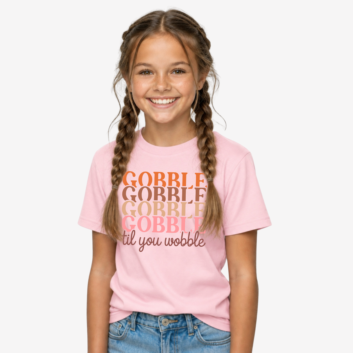 Girl modeling a light pink youth T-shirt with the retro Gobble Til You Wobble Thanksgiving design.