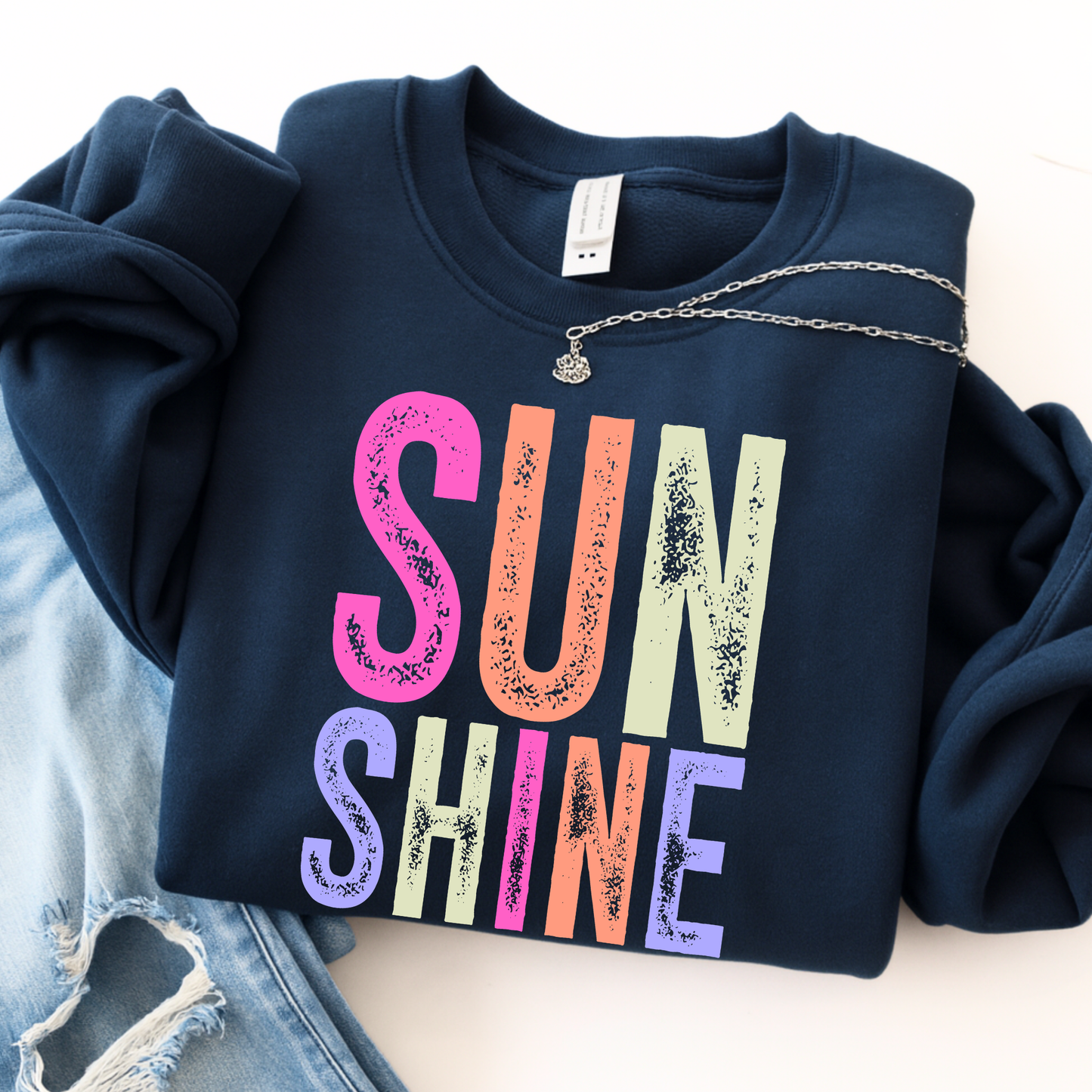 Navy blue sweatshirt with 'SUNSHINE' in colorful letters on a light background