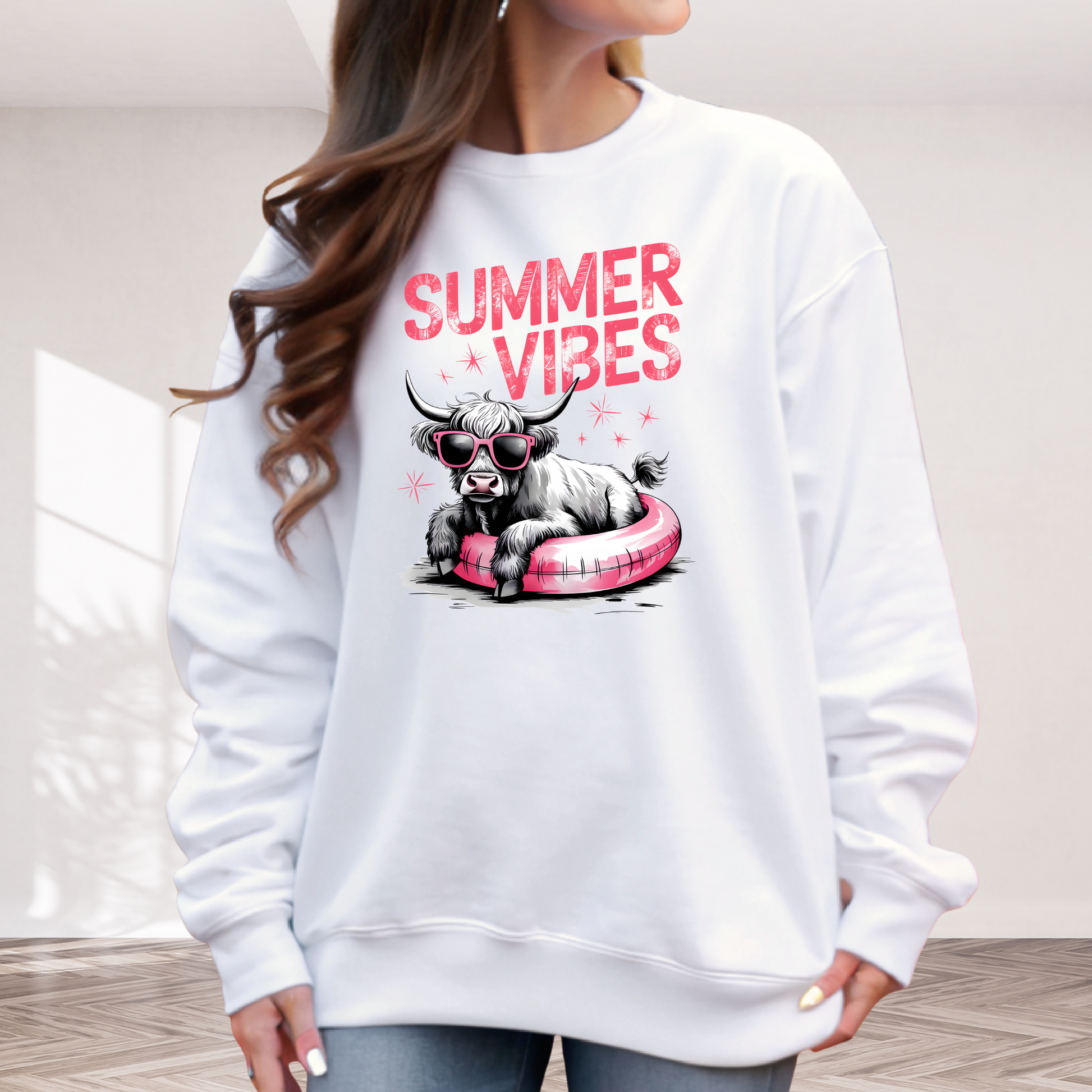 White sweatshirt with 'Summer Vibes' graphic design featuring a highland  cow on a pink pool float.