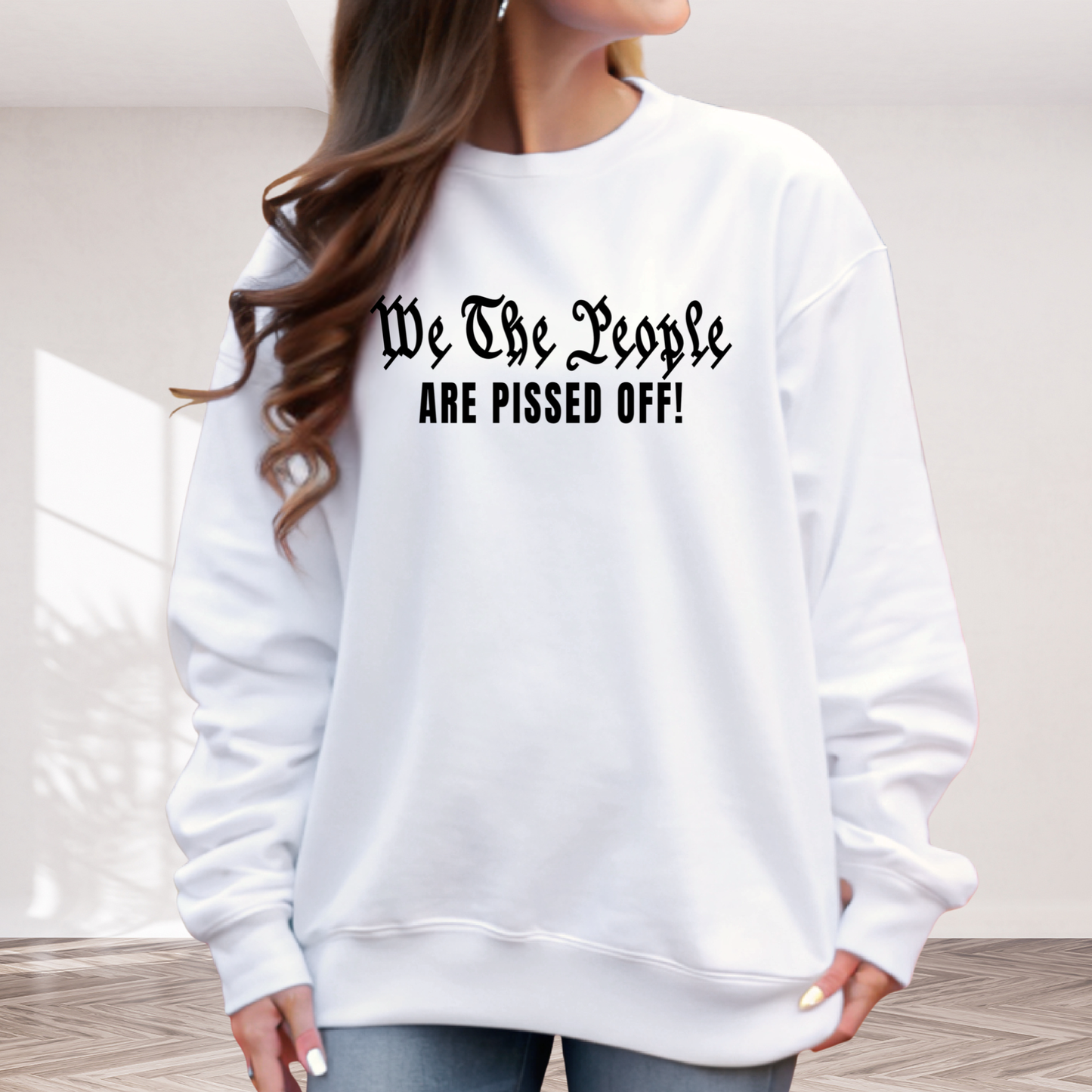 White sweatshirt with text 'We The People ARE PISSED OFF!' worn by a person indoors.