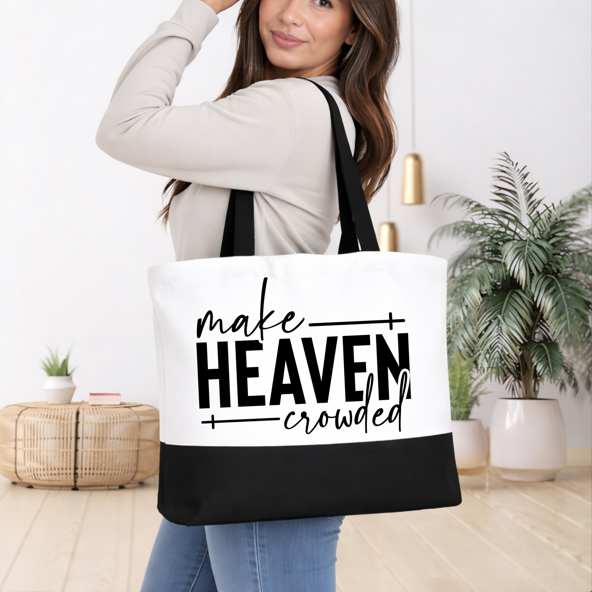 Woman holding black and white Christian tote bag with Make Heaven Crowded faith message and reinforced straps