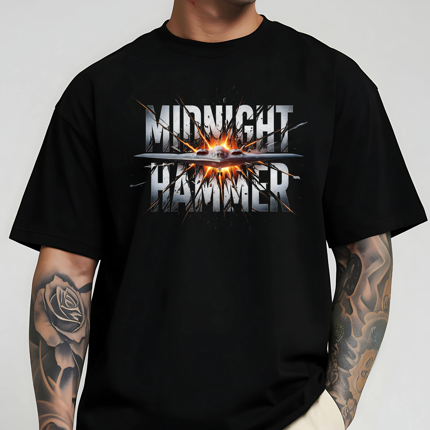 Oversized Midnight Hammer stealth bomber graphic tee on male model – black shirt with silver text and fire burst