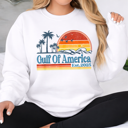 White sweatshirt with 'Gulf Of America Est. 2025' design featuring palm trees and a sunset.