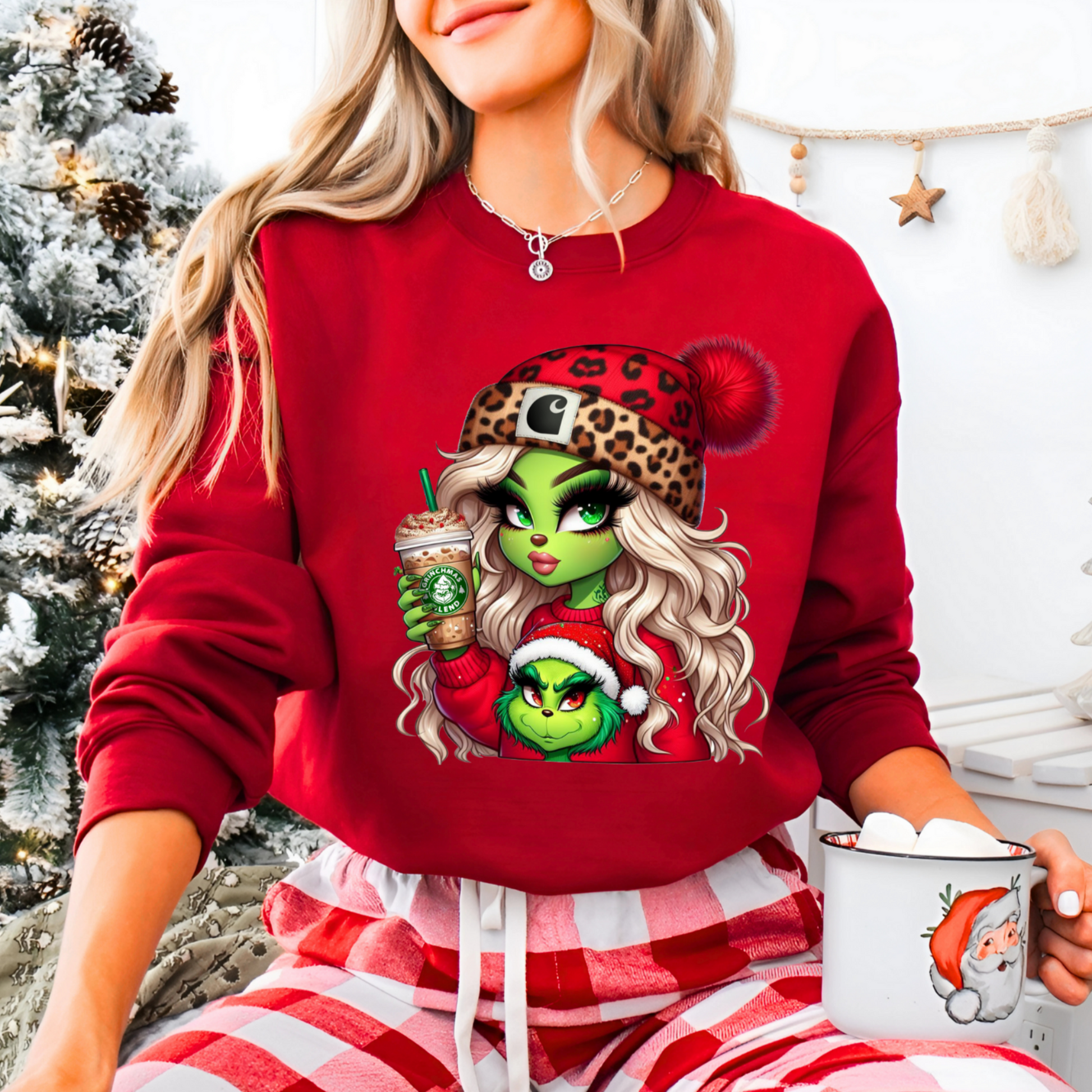 Woman wearing a red Christmas shirt with a green-skinned cartoon girl holding a holiday drink and a festive companion in a Santa hat.