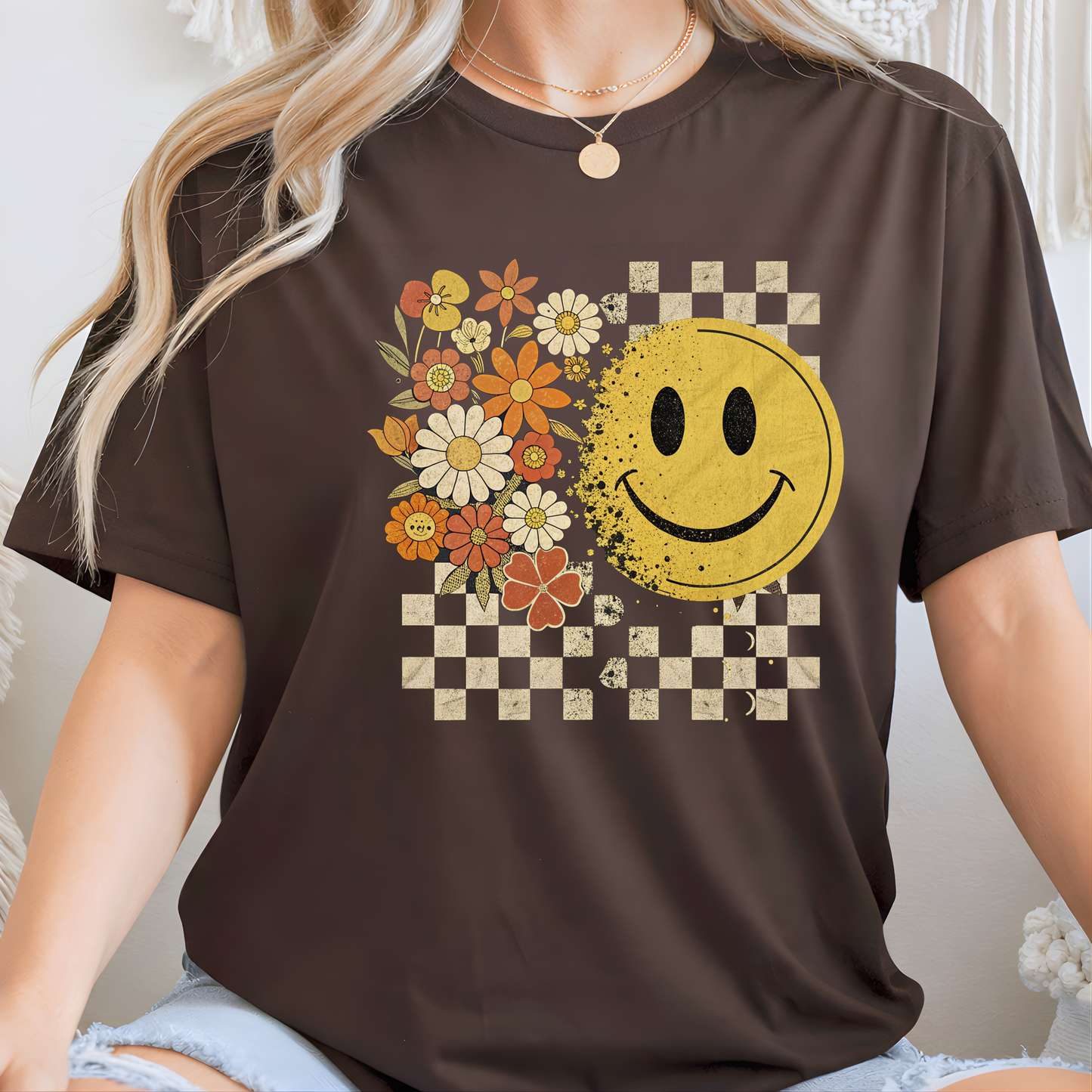 Lady wearing a brown t-shirt with a smiley face and floral design.