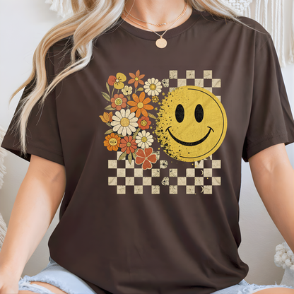 Lady wearing a brown t-shirt with a smiley face and floral design.