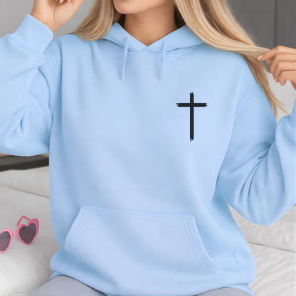Light blue hoodie with a black cross on the chest, worn by a person.
