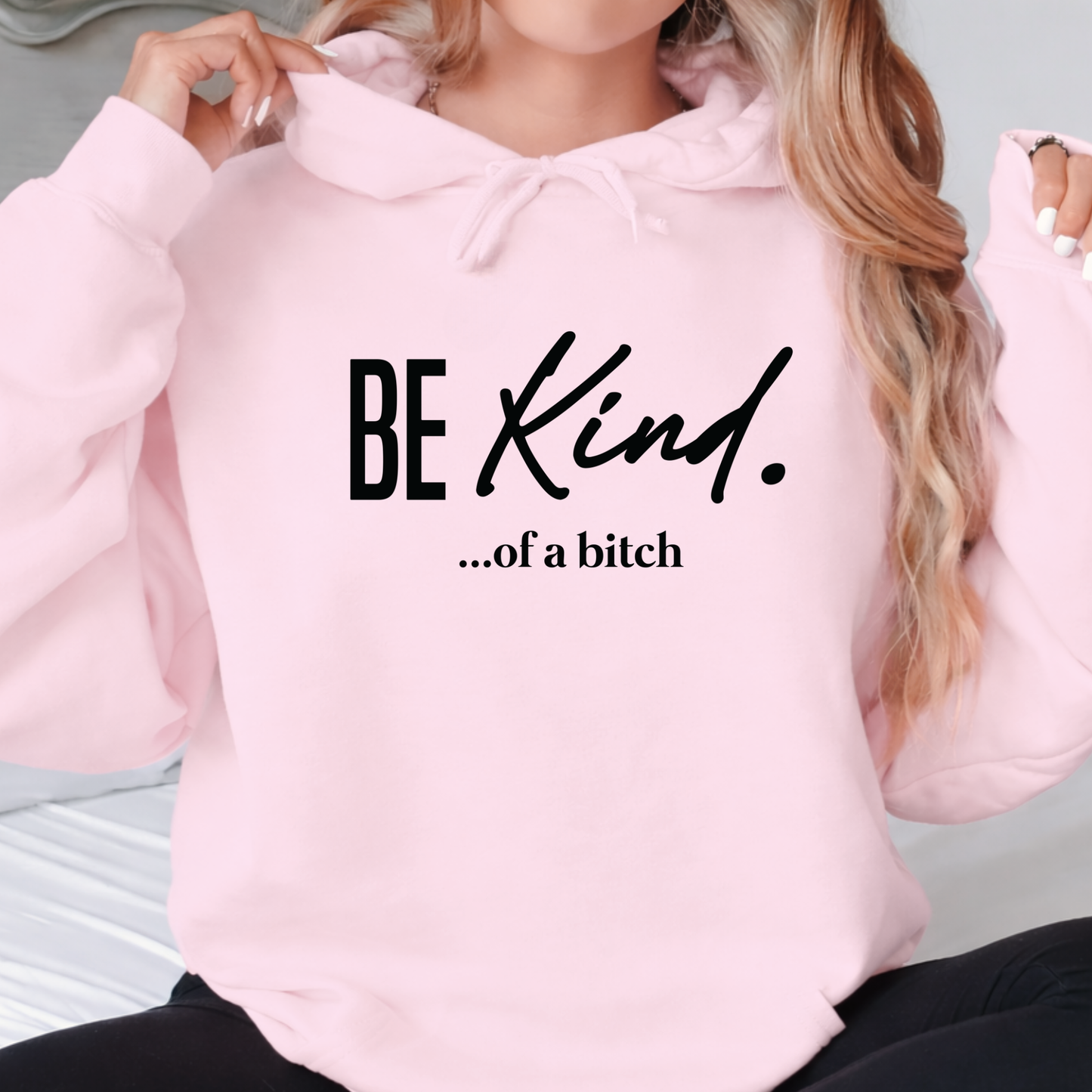 Pink hoodie with 'BE Kind. ...of a bitch' text worn by a person.