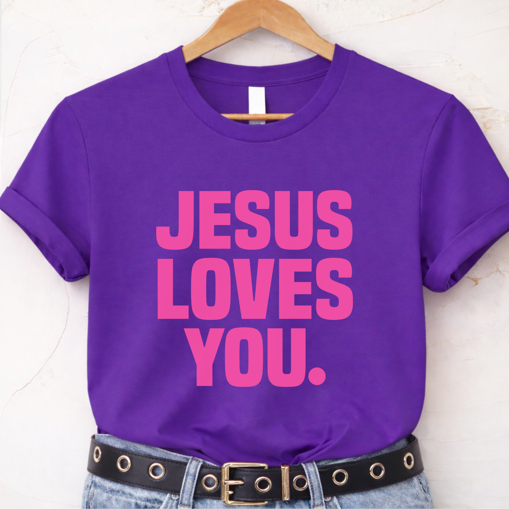 Purple t-shirt with 'Jesus Loves You' text on a hanger