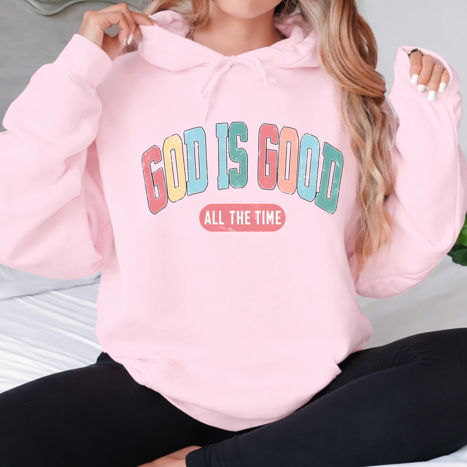 Person wearing a pink hoodie with 'GOD IS GOOD ALL THE TIME' text.