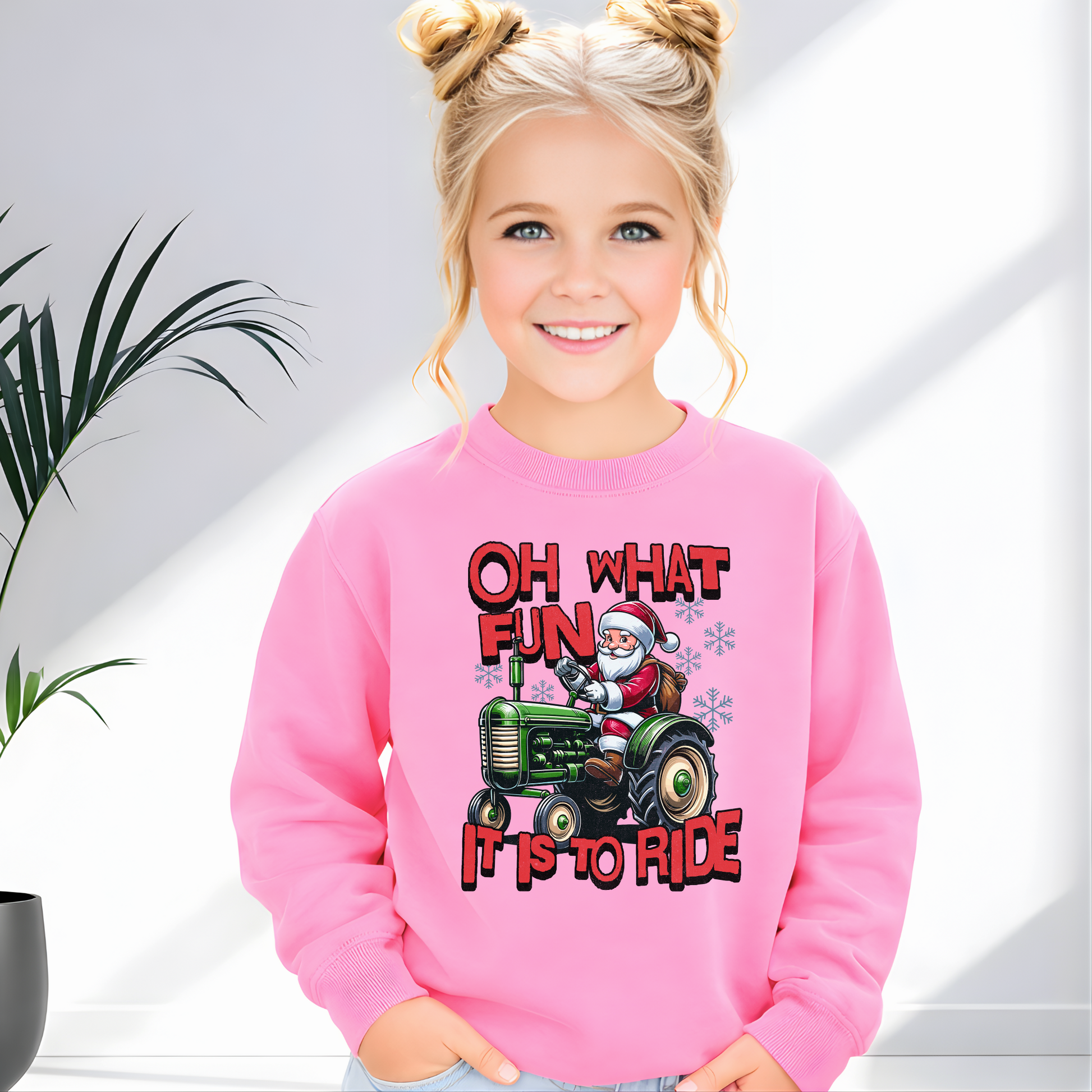 Child wearing a pink sweatshirt with a Christmas design featuring Santa and a tractor.