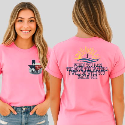 Woman wearing a pink t-shirt with a graphic design and blue jeans against a plain background