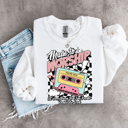 White Made to Worship crewneck sweatshirt flat lay with a retro cassette graphic, styled with denim.