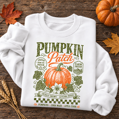 White sweatshirt with vintage Pumpkin Patch pumpkin and floral design arranged on a rustic wood table with fall leaves and pumpkins