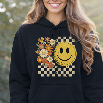 Woman wearing a black retro hoodie with a smiley face and floral design, standing outdoors.