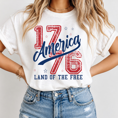 Person wearing a white t-shirt with 'America 1776 Land of the Free' design.