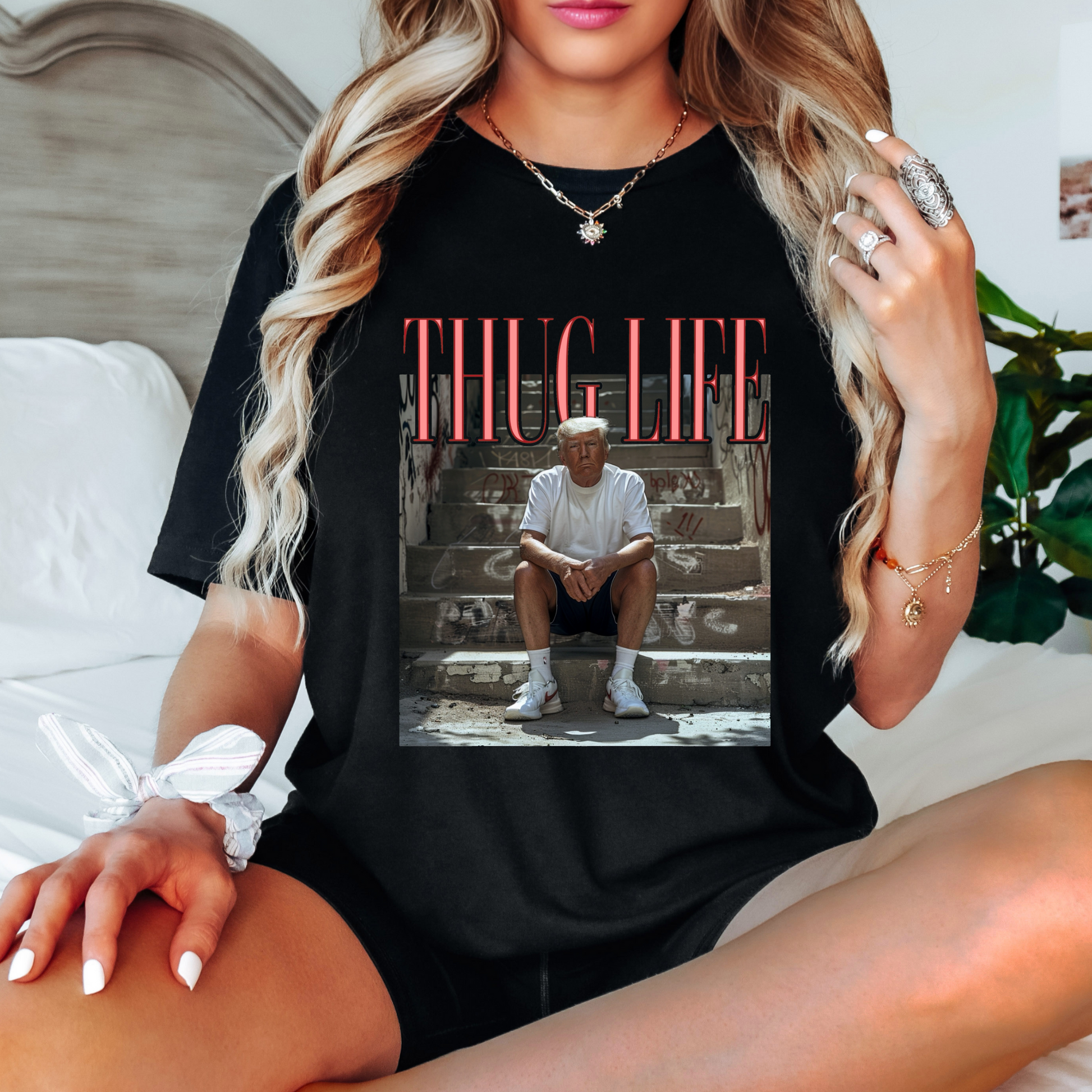 A person wearing a white crew neck t-shirt with a graphic print of a man sitting on steps and the text 'THUG LIFE' above the image.