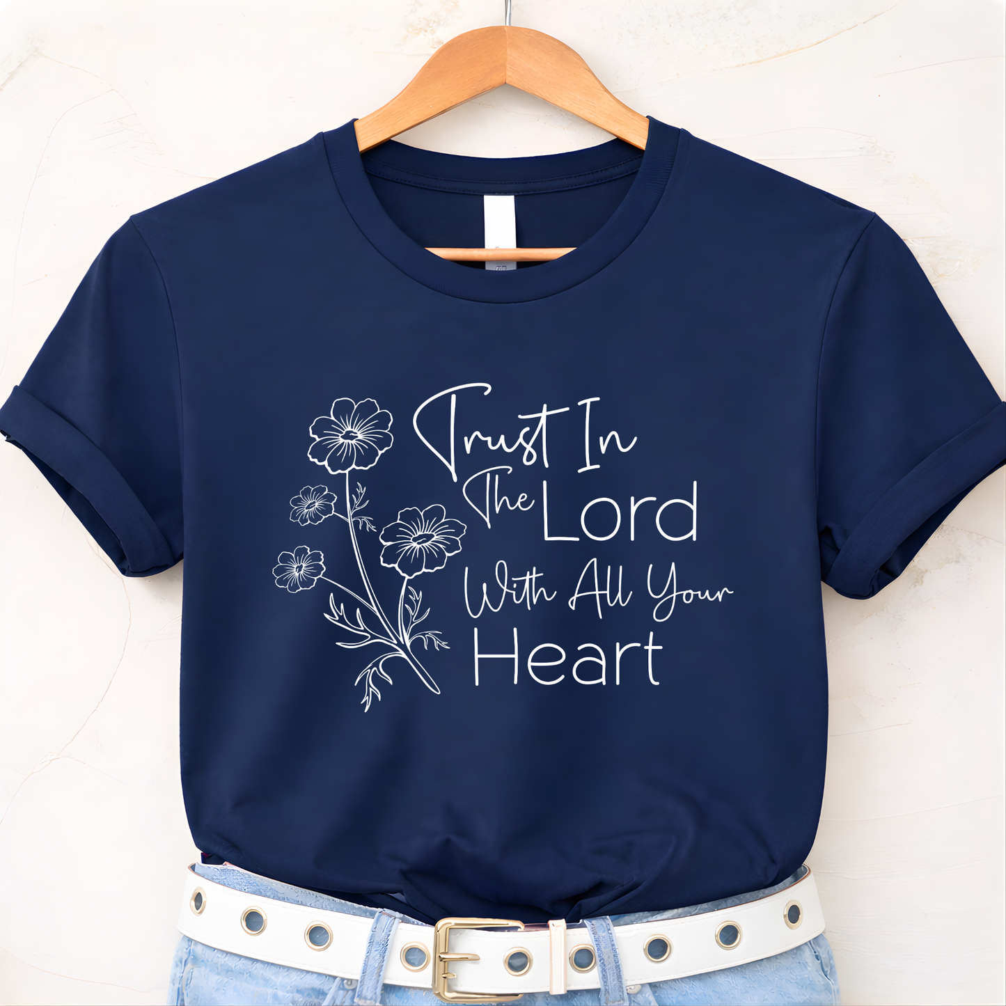 Navy blue t-shirt with floral design and text on a hanger against a white background