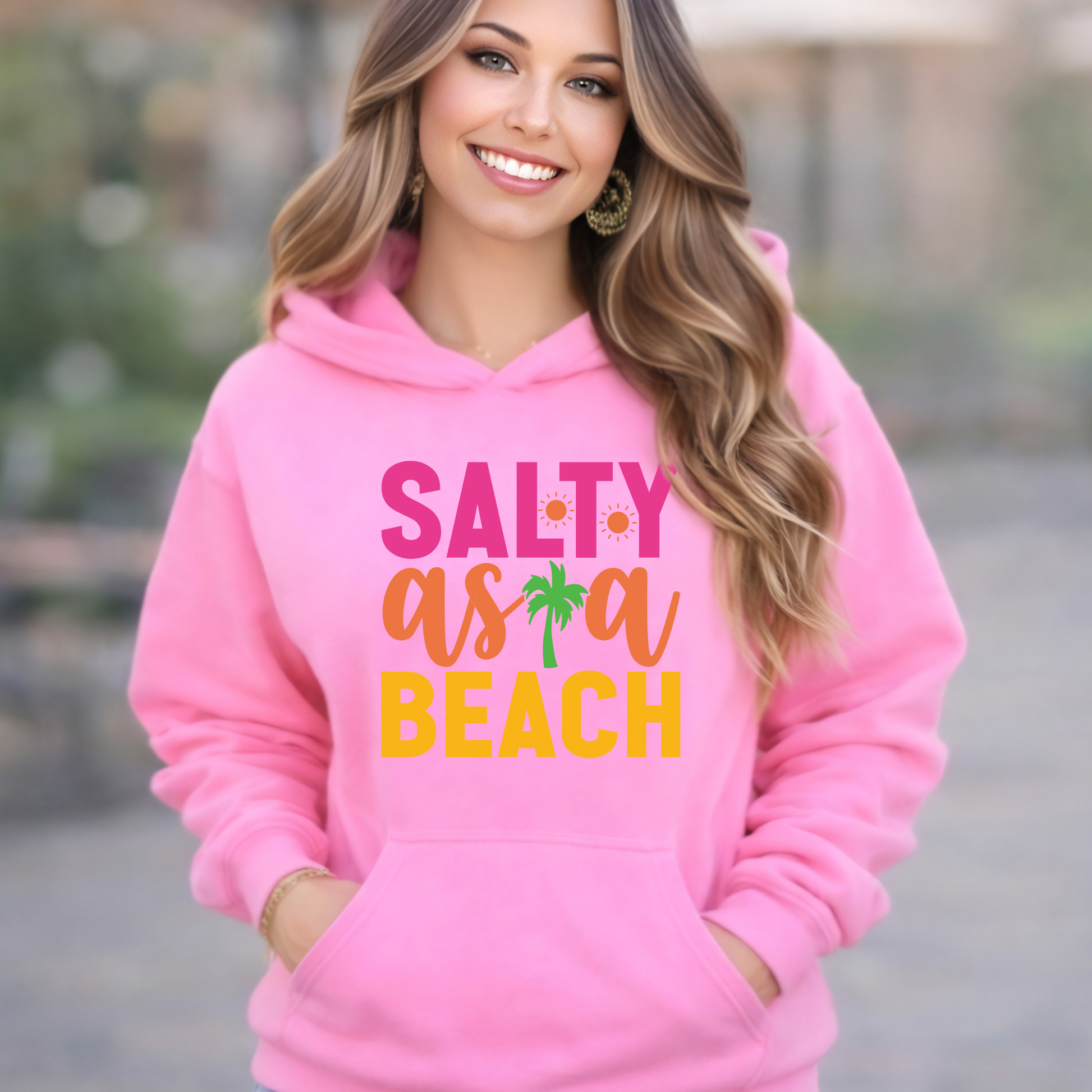Woman wearing a pink hoodie with 'Salty as a Beach' text