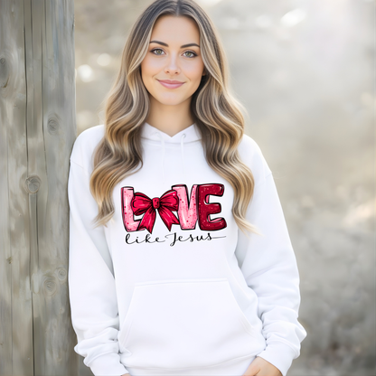 Woman wearing a white hoodie with 'Love like Jesus' design, standing against a wooden background.