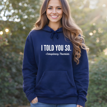 Woman wearing a navy blue Conspiracy Threorists hoodie with text, standing outdoors.