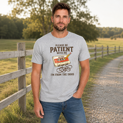 Man wearing a sports gray T-shirt featuring the Please Be Patient With Me, I’m From the 1900s cassette tape design.