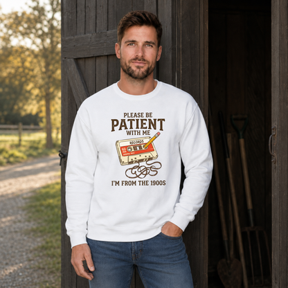 Man wearing a white crewneck sweatshirt featuring the Please Be Patient With Me, I’m From the 1900s graphic.