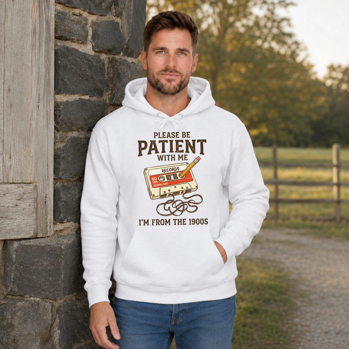 Man wearing a white hoodie with the Please Be Patient With Me, I’m From the 1900s cassette tape and pencil graphic.