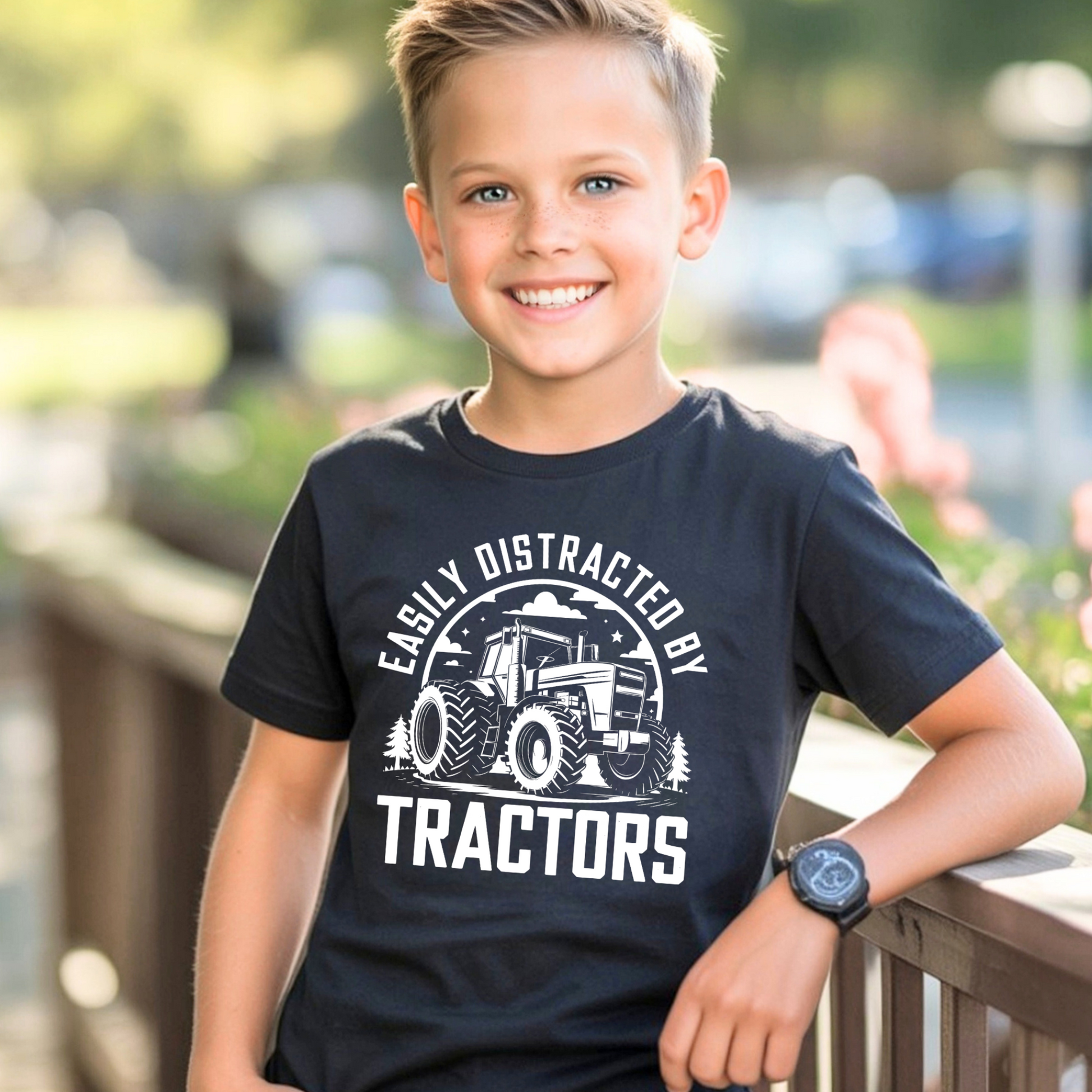 Smiling boy wearing navy Easily Distracted by Tractors youth t-shirt outdoors