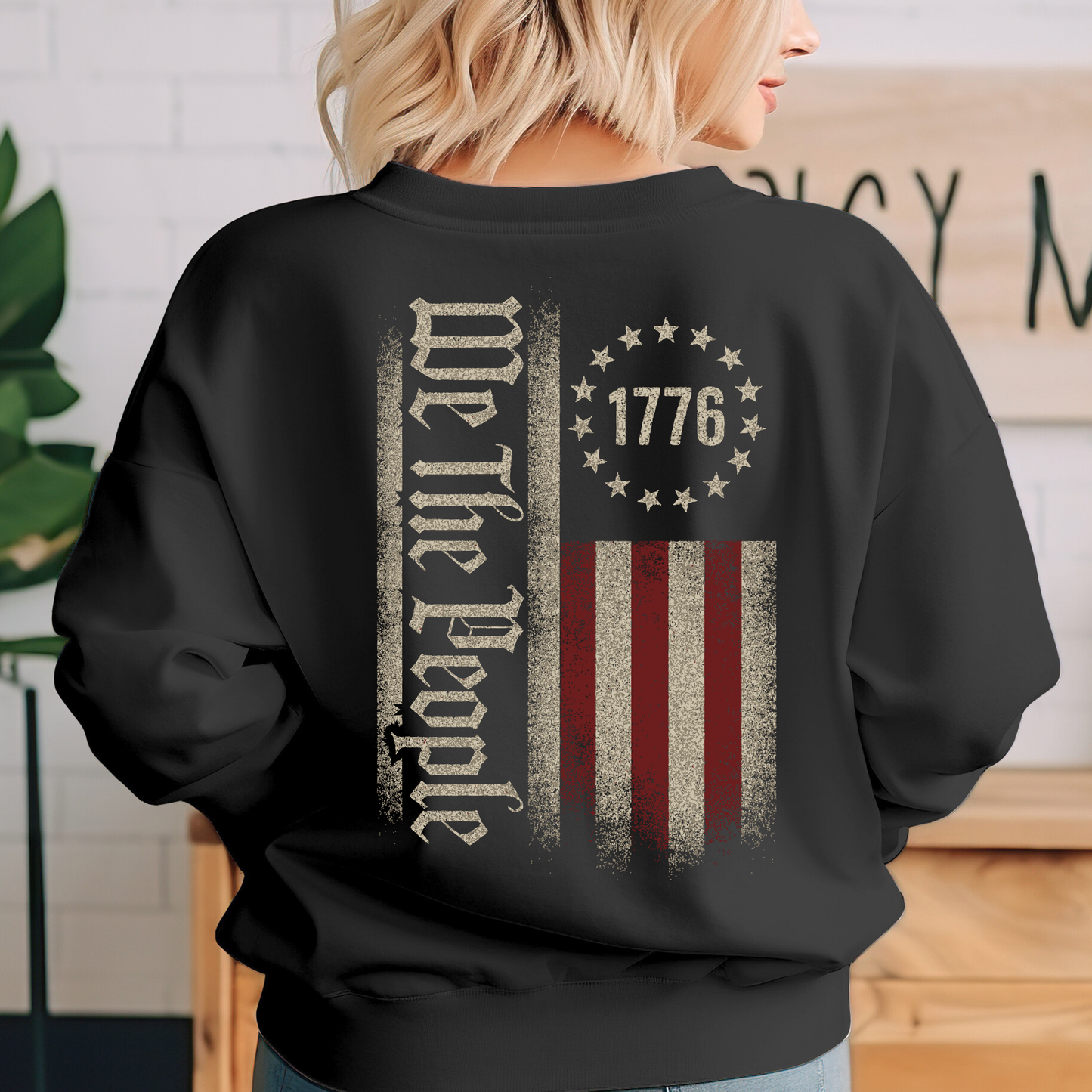 Person wearing a black sweatshirt with 'We the People' and '1776' design.