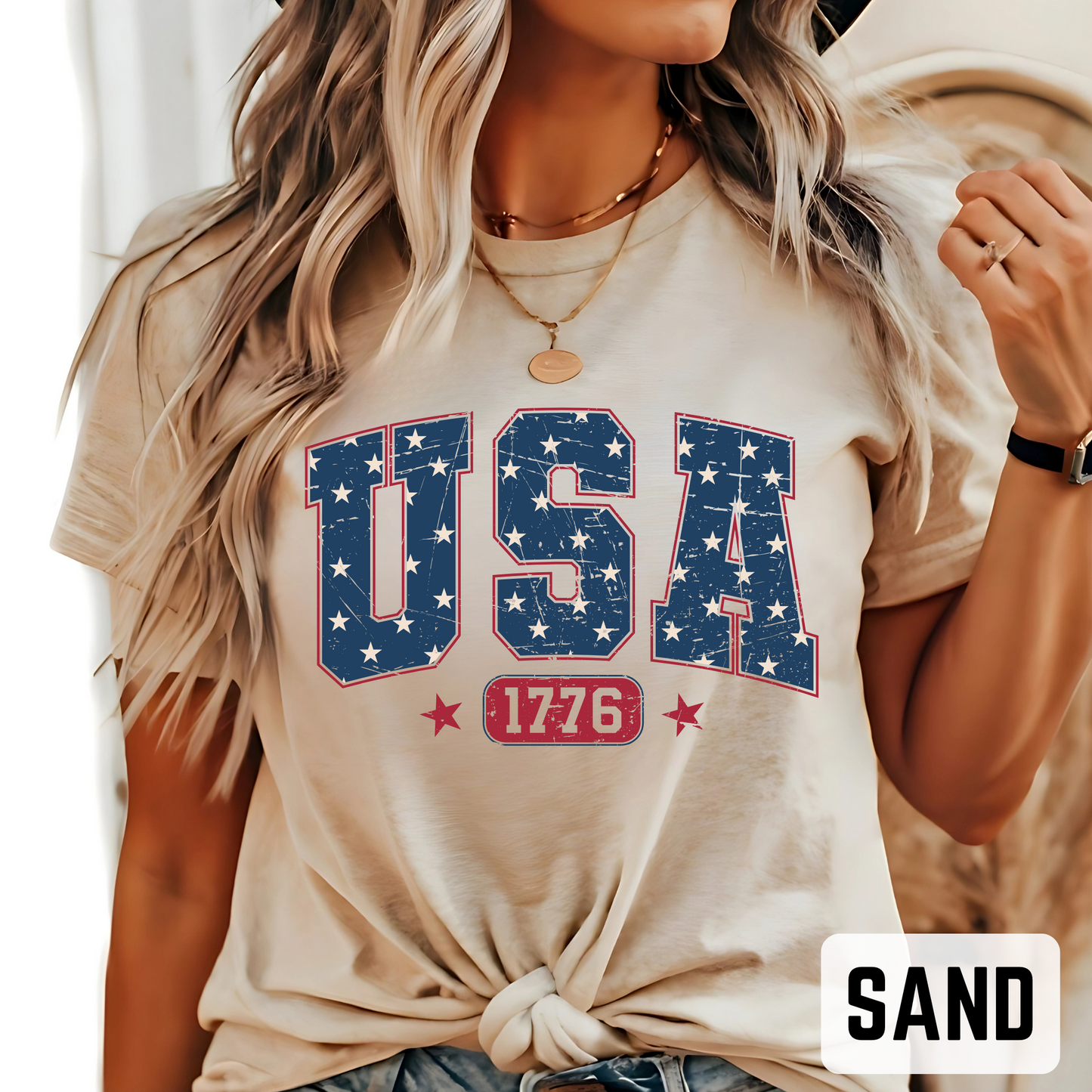 Woman wearing sand-colored USA 1776 patriotic T-shirt with distressed navy and red graphic, casual summer outfit