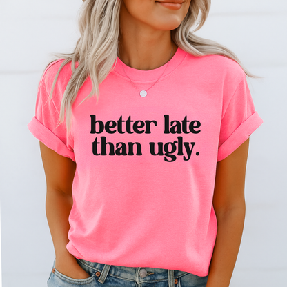 Person wearing a pink t-shirt with 'better late than ugly' text on a white background