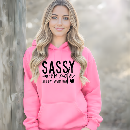 Woman wearing a pink hoodie with 'Sassy Mode All Day Every Day' text.