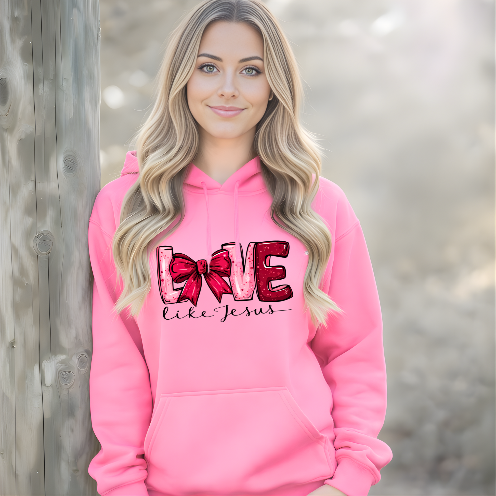 Woman wearing a pink hoodie with 'Love like Jesus' text and bow design.