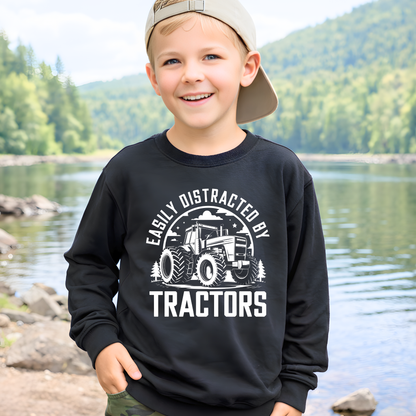 Young boy wearing black Easily Distracted by Tractors youth sweatshirt by river