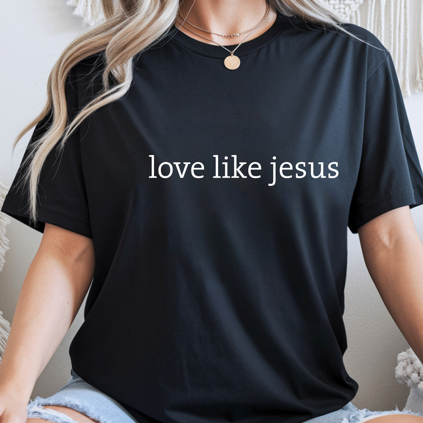 Woman in black “Love Like Jesus” shirt with plaid flannel, cozy indoor style